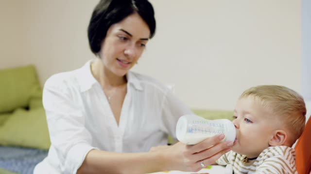 Young-mother-feed-a-little-son-with-milk