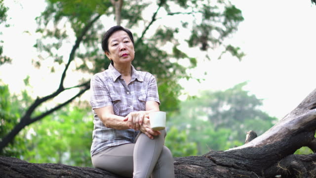 Solitaria-mujer-senior-asiática-sentada-mirando-triste-café-beber-solo-en-el-pensamiento-de-park-acerca-de-la-vida