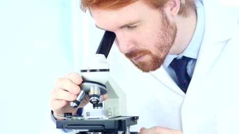 Rothaarige-Chemiker,-wissenschaftliche-Reseacher-arbeiten-am-Mikroskop-im-Labor