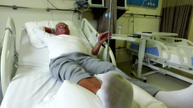 Elderly-70-plus-year-old-man-recovering-from-surgery-in-a-hospital-bed