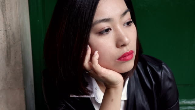 Mujer-China-joven-triste-y-pensativa-sentado-en-pasos-en-el-camino-constante-cam