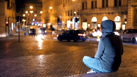 Young-person-with-hood-contemplates-the-city-at-night