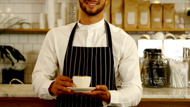 Smiling-waiter-serving-cup-of-coffee-4k