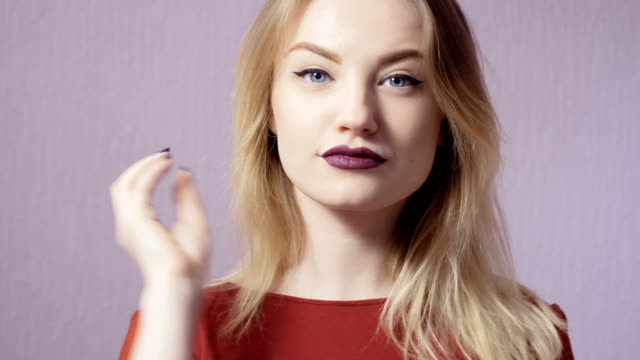 Glückliches-Mädchen-mit-Make-up-und-lila-Lippen-auf-violettem-Hintergrund