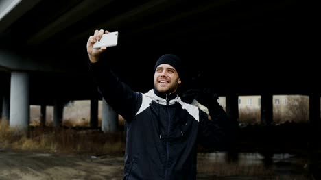 Happy-sportive-man-taking-selfie-portrait-with-smartphone-after-training-in-urban-outdoors-location-in-winter