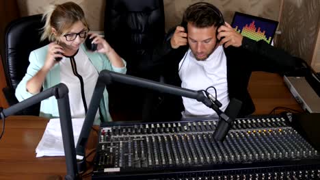 man-and-woman-in-headphones-communicate-with-each-other-beside-microphone