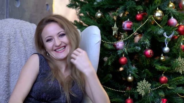 Junge-attraktive-glücklich-Frau-lachen,-Lächeln-und-sitzen-auf-Weihnachtsbaum-Hintergrund.