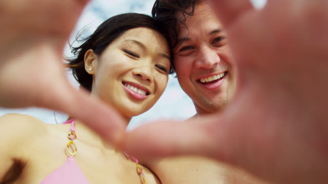 Portrait-Ethnic-Couple-making-heart-shape-hands-selfie