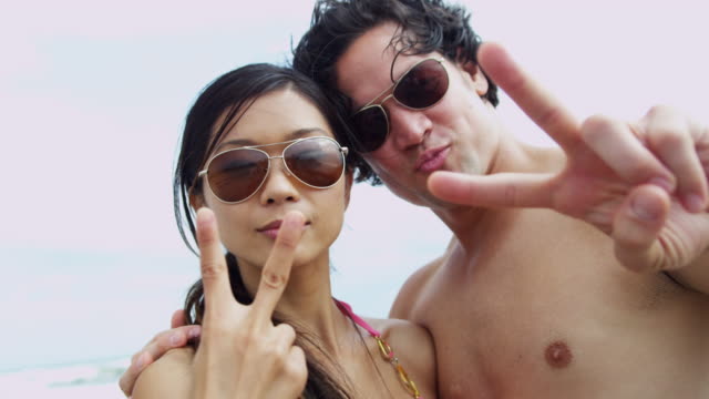 Portrait-Ethnic-couple-filming-beach-vacation-video-selfie