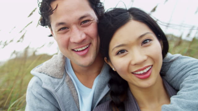 Portrait-Smiling-Young-Asian-Chinese-Couple-Fall-Beach