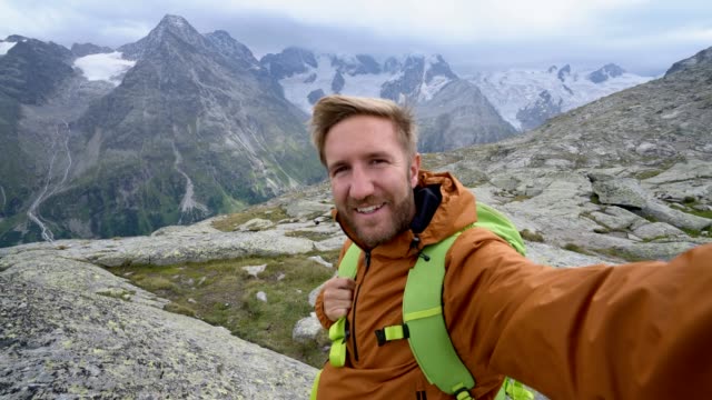 Junger-Mann-auf-einem-Berg-nimmt-ein-Selfie-Porträt-mit-Blick-auf-den-Gletscher