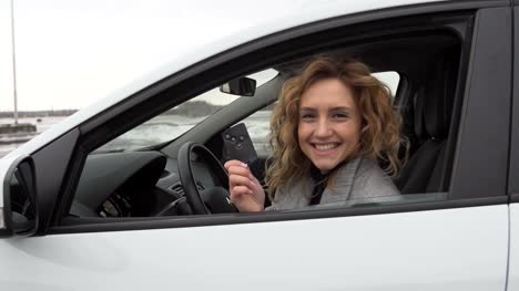 Young-woman-showing-key-to-new-car