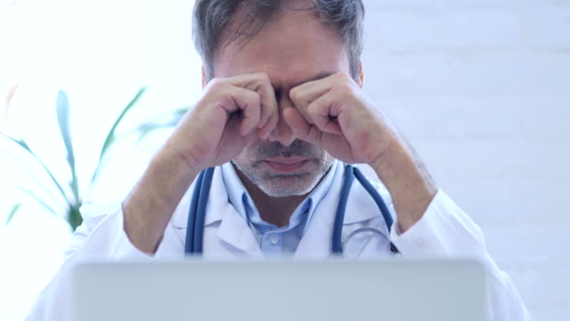 Tired-Doctor-Rubbing-Eyes-while-working-in-Clinic,-Close-Up