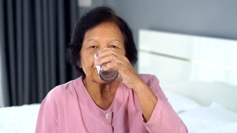 ältere-Frau-Trinkwasser-im-Schlafzimmer
