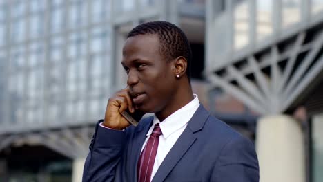 self-confident-balck-business-man-talking-by-phone-in-the-street