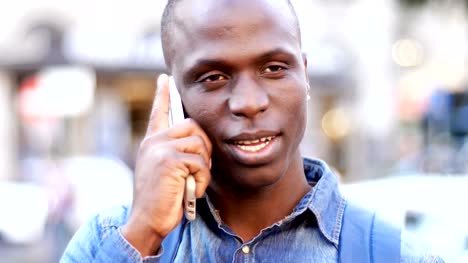 handsome-black-african-man-talking-by-phone-in-the-street--close-up
