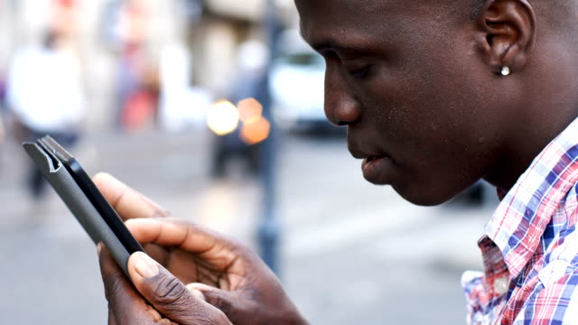 African-black-man-using-digital-tablet-in-the-street