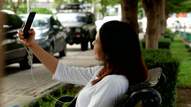 Hermosa-mujer-tener-chat-de-vídeo-usando-el-teléfono-inteligente-al-aire-libre-en-parque-público.