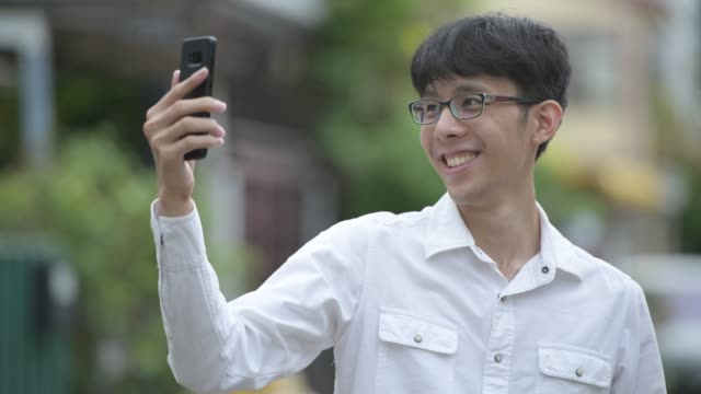 Glücklich-asiatischen-Jungunternehmer-Videotelefonie-in-der-Straßen-Natur