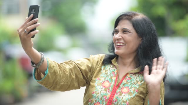 Madura-feliz-hermosa-mujer-India-video-llamada-en-el-exterior-de-las-calles