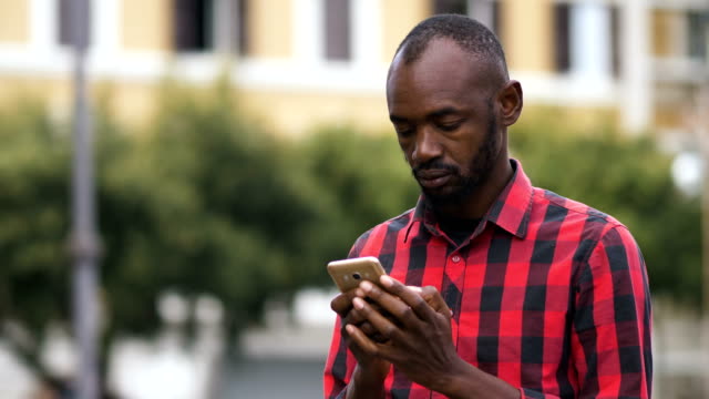 black-african-man-typing-on-smartphone-in-the-street