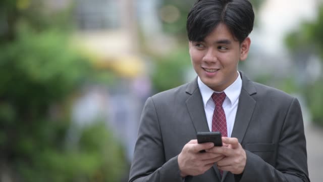 Schöne-asiatische-Jungunternehmer-mit-Telefon-in-den-Straßen-im-freien