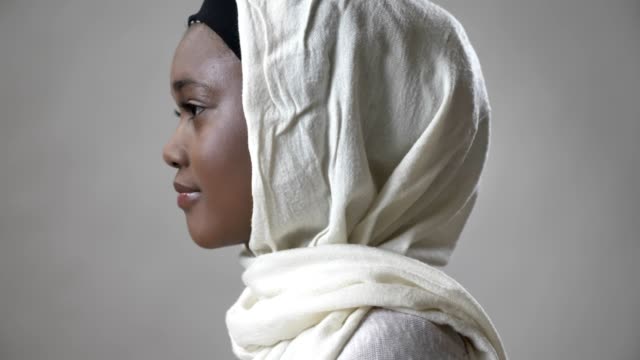 Junge-afrikanische-muslimisches-Mädchen-Hijab-ist-Kopf-zu-drehen-und-schauen-in-die-Kamera,-Religioun-Konzept,-grauen-Hintergrund