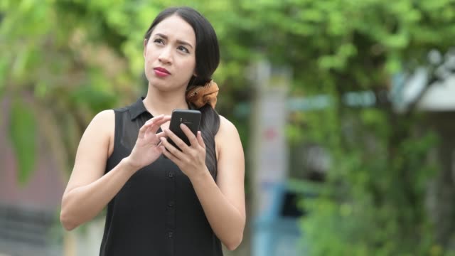 Junge-schöne-asiatische-geschäftsfrau-mit-Telefon-in-den-Straßen-im-freien