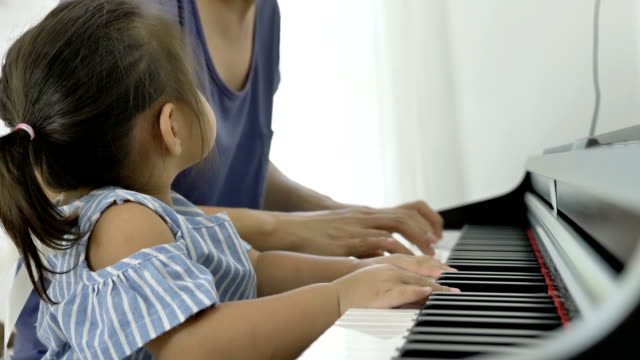 4K-:-Slow-motion-of-Asian-girl-playing-piano-with-her-mother