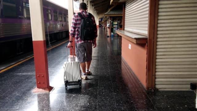 Los-turistas-a-pie-arrastre-equipaje-en-la-estación-de-tren.-Concepto-de-trabajo-y-viajes.