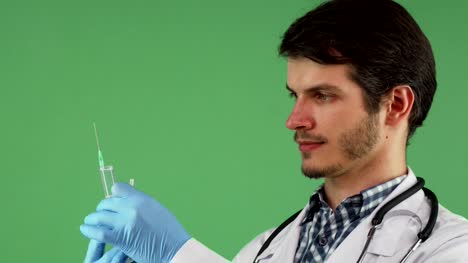 Männliche-medizinische-Arbeiter,-die-mit-einer-Spritze-auf-grünem-Hintergrund