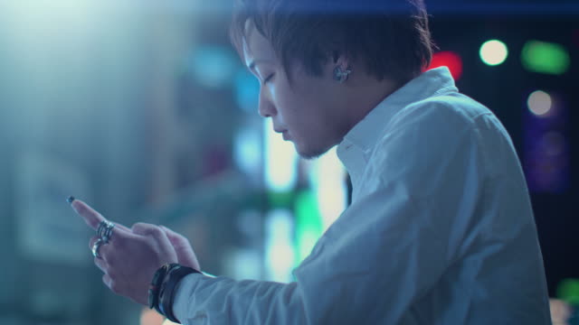 Portrait-of-the-Handsome-Alternative-Japanese-Boy-Using-Smartphone.-In-the-Background-Big-City-Advertising-Billboards-Lights-Glow-in-the-Night.