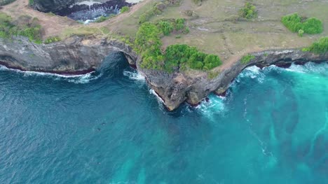 Luftaufnahme-von-Drohne-4k-Kamera.-Felsküste-mit-hohen-Klippen,-Meer-Surfen-mit-brechenden-Wellen-an-der-Küste,-Nusa-Penida,-Pasih-Uug,-Broken-Strand.