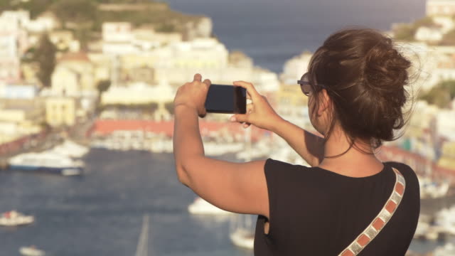 Glückliche-junge-Frau-touristischen-Smartphone-Fotografieren-der-Stadt-auf-der-Insel-Ponza-in-Italien-traditionell-Meer-Stadtlandschaft