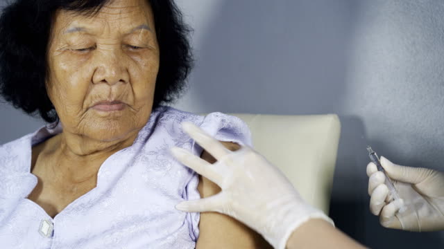 Doctor-giving-vaccine-injection-into-senior-woman-shoulder