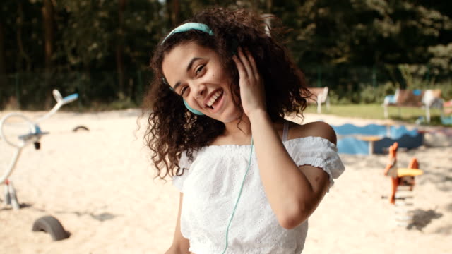 Glückliche-junge-Afro-Amerikanerin-mit-Kopfhörern-Musik-und-ihren-Urlaub-genießen.