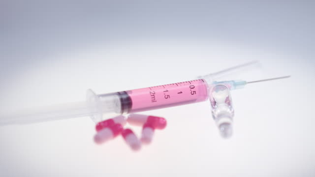 Syringe-with-pink-liquid.-Pharmaceutical-pills-and-medical-glass-ampule