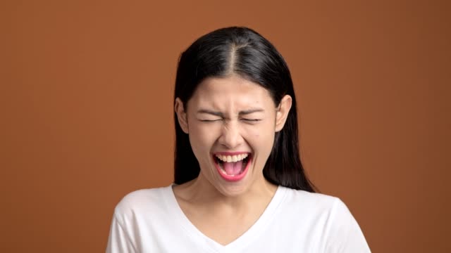 Angry-woman-isolated.-Portrait-of-asian-woman-in-white-t-shirt-screaming-out-loud-looking-at-camera.