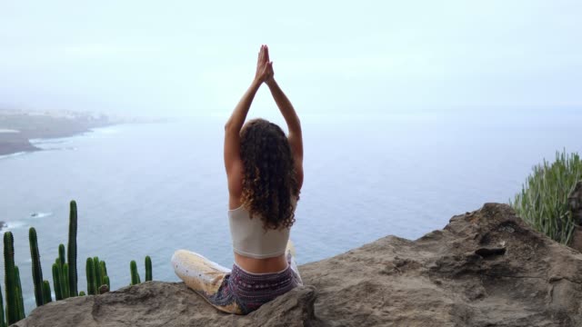 Woman-meditating-on-top-of-a-rock-at-the-mountains-at-sunrise.-Practice-yoga-on-outdoor.