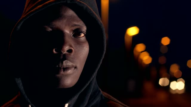 Nachdenklich-traurig-einsam-schwarzen-afrikanischen-Mann-mit-Kapuze-Blick-auf-Kamera-City-Nacht