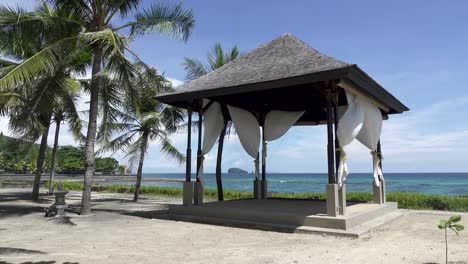 Arbor-among-palm-trees-on-the-bank-of-the-tropical-beach-in-the-sea-resort