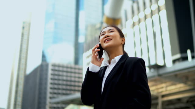 Hübsche-Geschäftsfrau-im-Gespräch-mit-Smartphone-bei-Outdoor-Büro