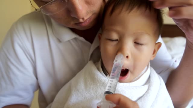 Asian-Parent-flushing-toddler-baby-boy-child-nose-with-syringe-for-Nasal-Irrigation
