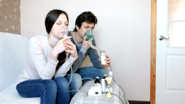 Use-nebulizer-and-inhaler-for-the-treatment.-Man-and-woman-inhaling-through-inhaler-mask.-Front-view.