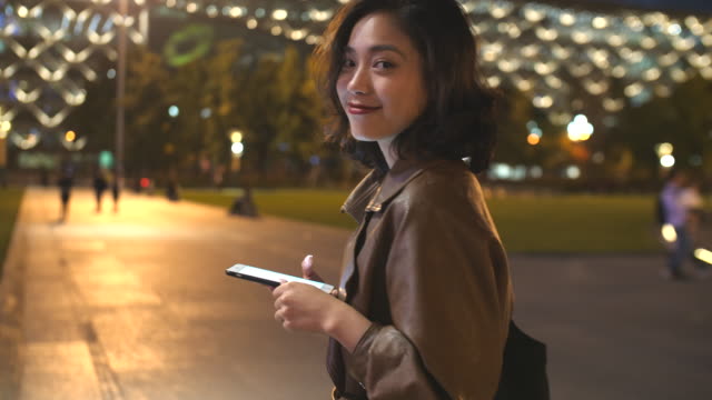 hübsche-junge-Asiatin-mit-Handy-in-der-Stadtstraße-in-der-Nacht,-4k