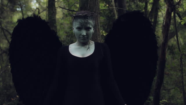 4k-Halloween-mujer-oscura-del-ángel-con-alas-de-negro-en-el-bosque-de-manos-se-levantan