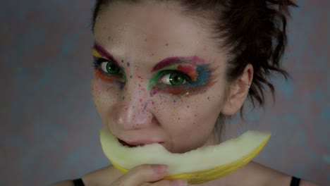 4k-Shot-of-a-Woman-with-Multicoloured-Make-up-eating-Melon