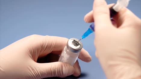 Doctor-piercing-the-lid-of-the-ampoule-with-syringe