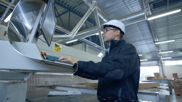 Ingeniero-que-usa-el-sombrero-duro-configurando-la-máquina-del-CNC-en-la-fábrica