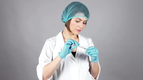 Joven-doctora-en-guantes-manteniendo-una-jeringa-y-preparando-la-inyección-aislada-sobre-fondo-gris.-Concepto-de-salud.-Rodada-en-4k